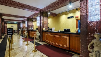 A reception area with marble flooring, a reception desk, and a statue.