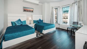 A hotel room with two beds, a desk, a chair, and a window with curtains.