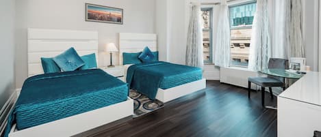 A hotel room with two beds, a desk, a chair, and a window with curtains.