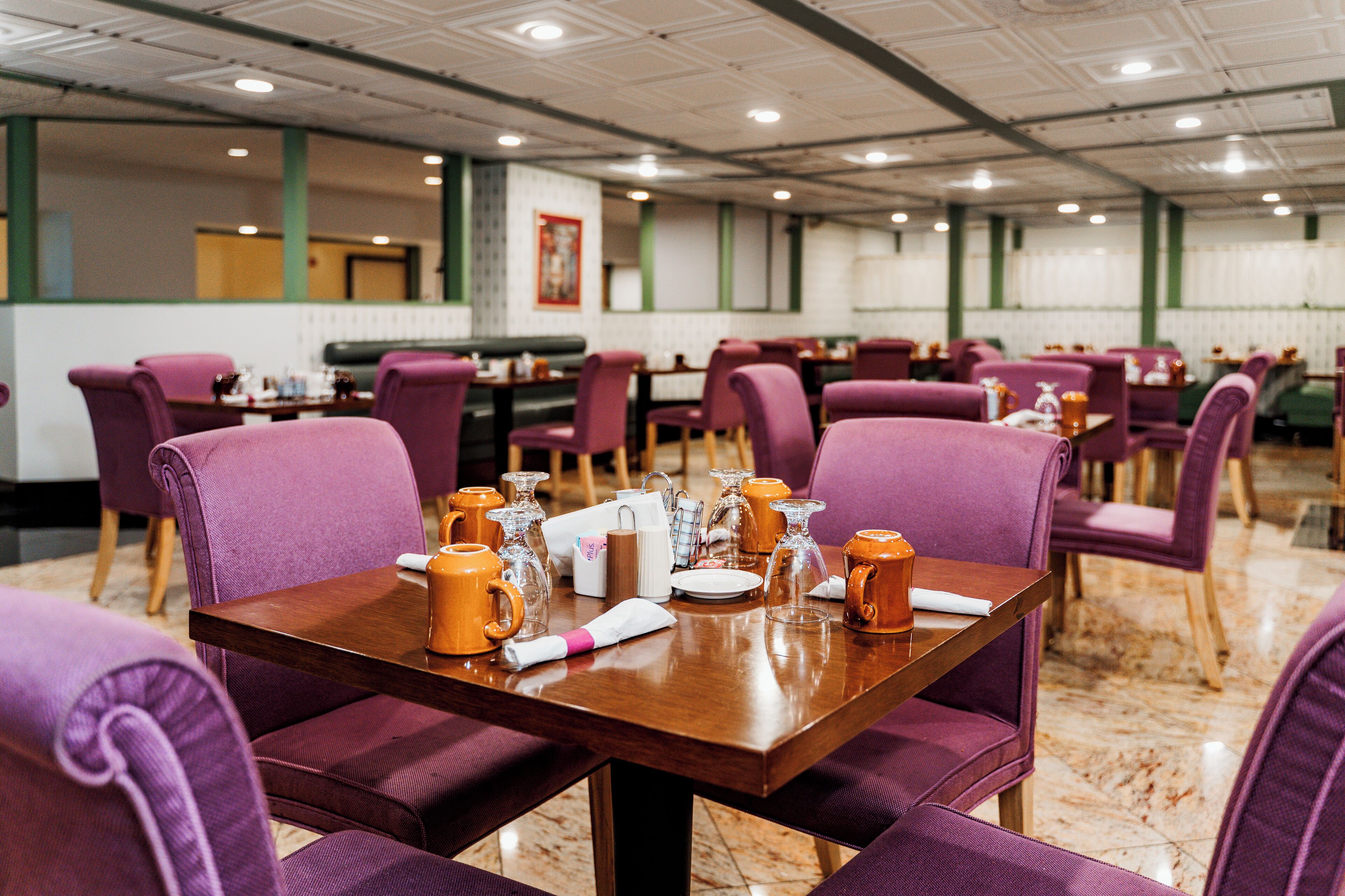 A dining area with purple upholstered chairs and a wooden table set for four.