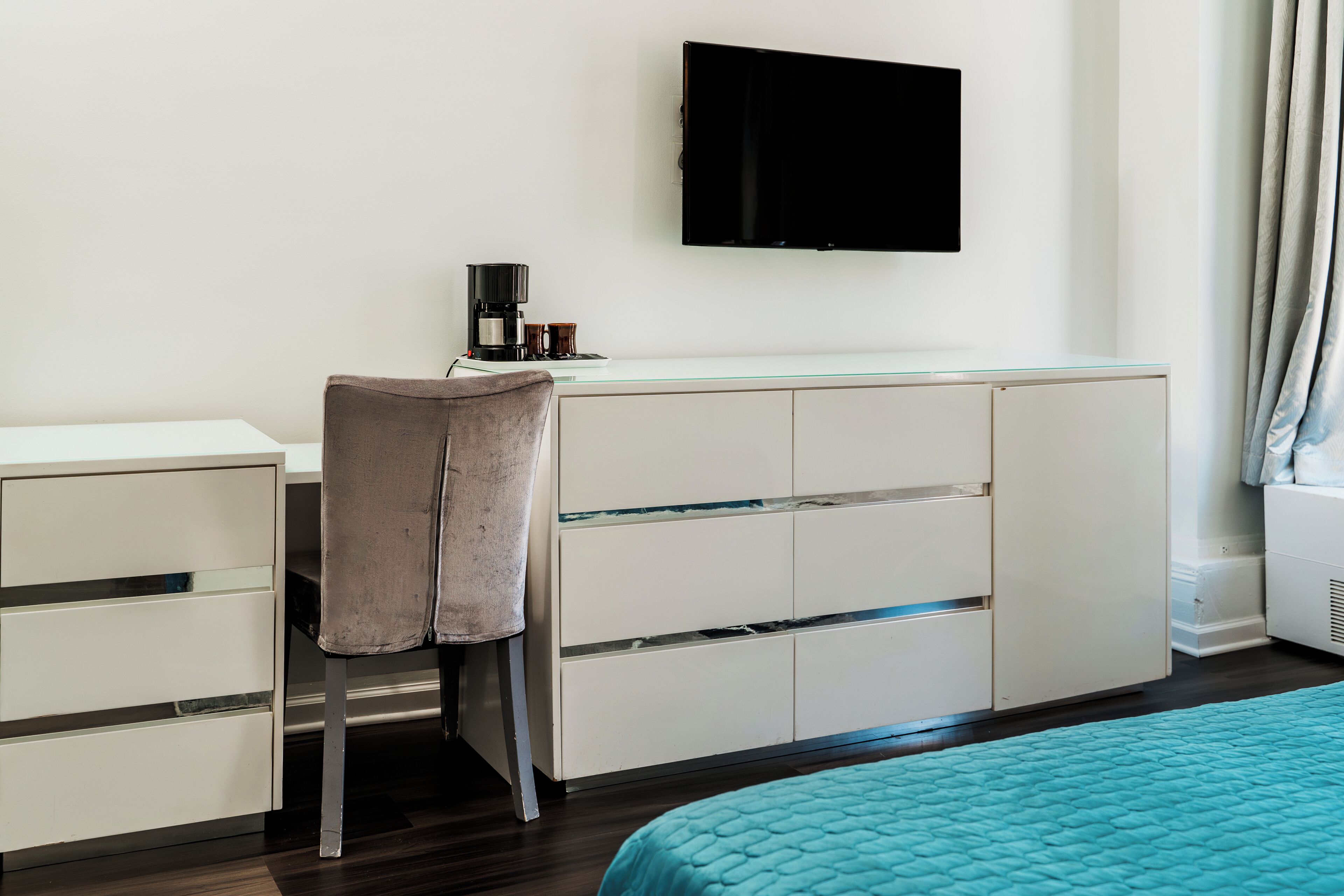 Une chambre d’hôtel moderne équipée d’un lit, d’un bureau avec une chaise, d’un téléviseur à écran plat et d’une machine à café.