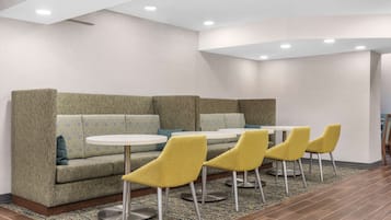 Un área de descanso moderna con un sofá y sillones amarillos alrededor de una mesa blanca.