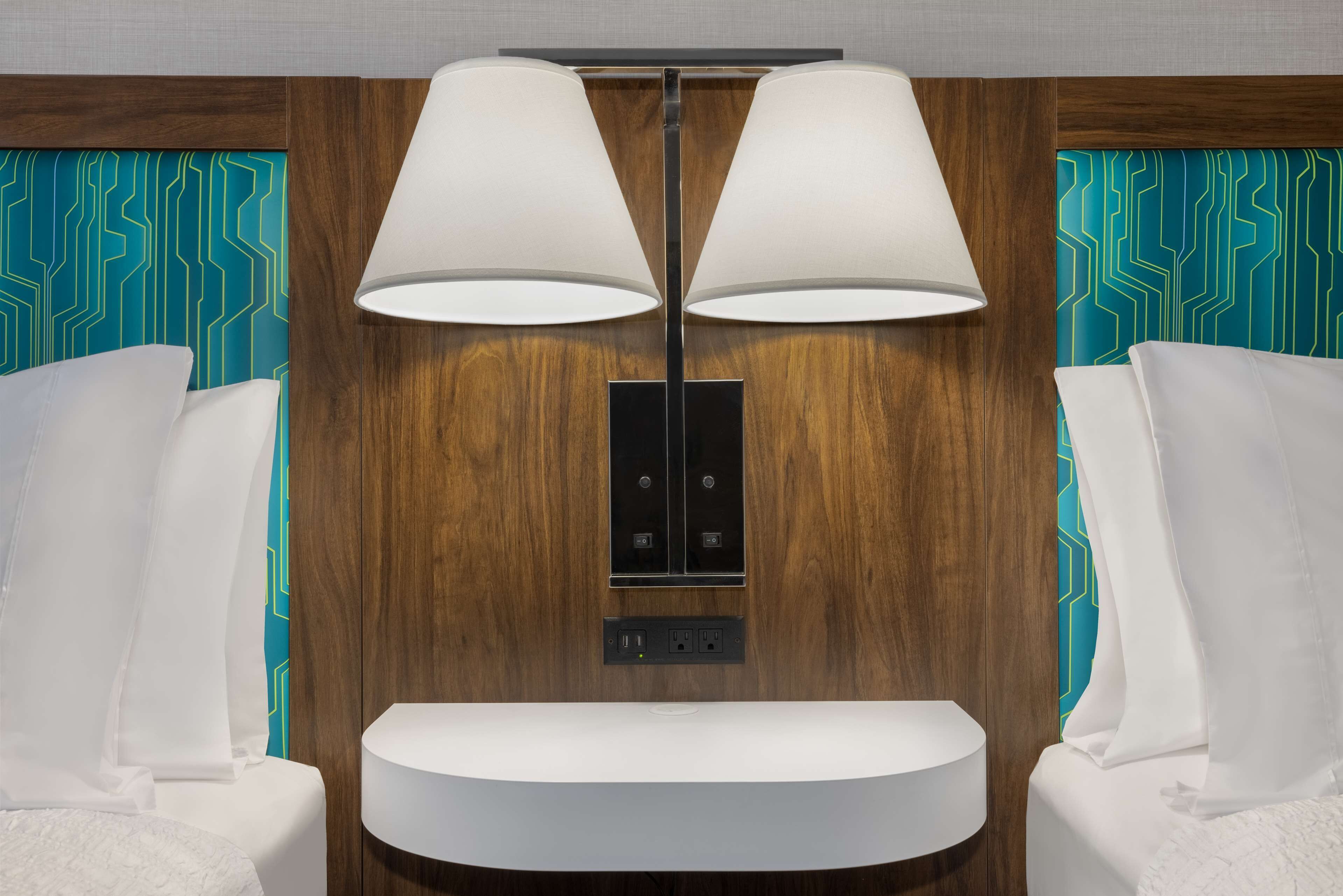 A modern bathroom with a wooden vanity, two wall-mounted lamps, and a mirror.