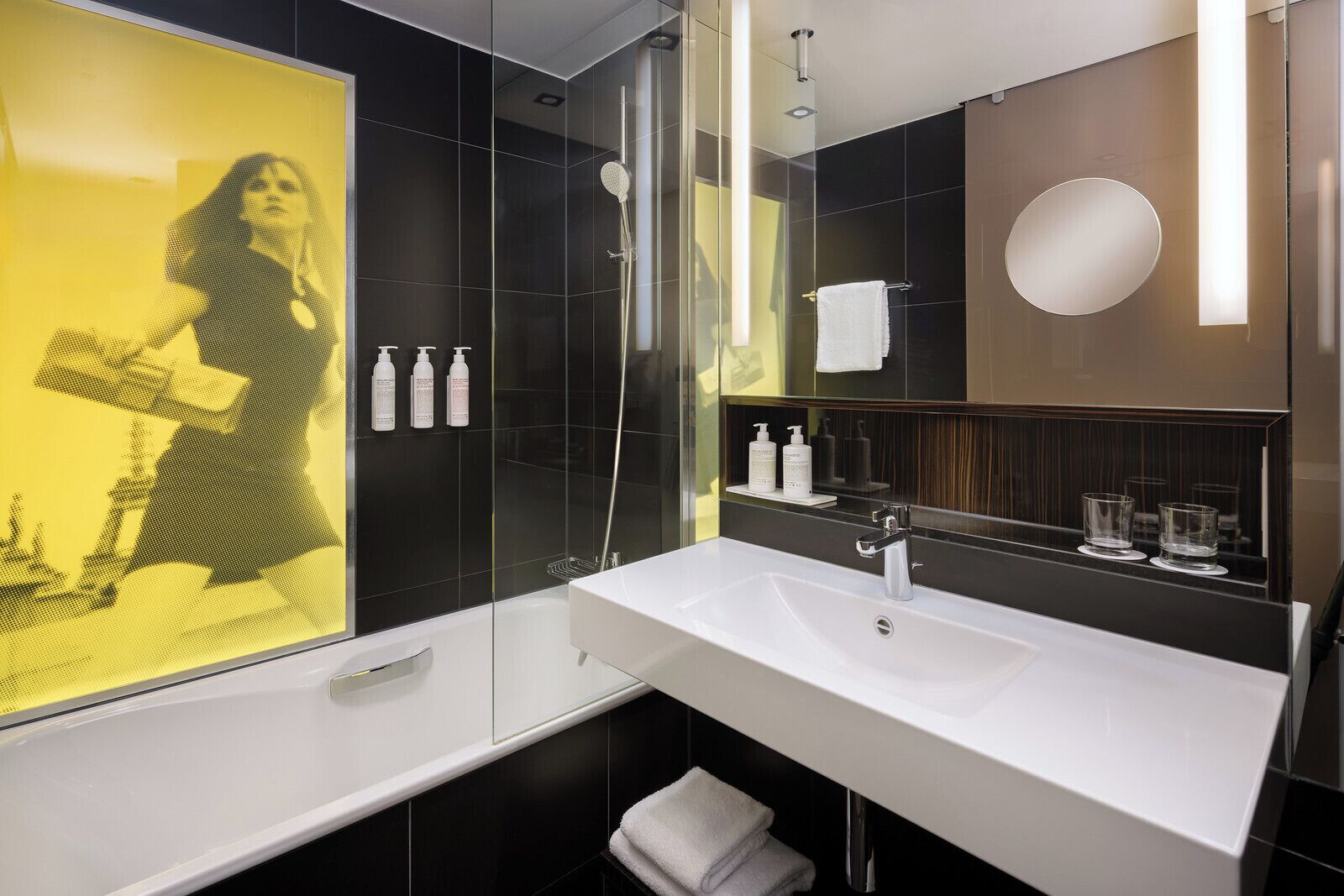 A modern bathroom with a white sink, a glass shower enclosure, and a large mirror.