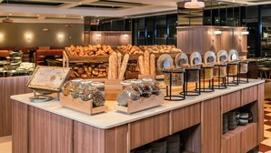 A buffet counter with various food items, including bread and jars of condiments. - Le Méridien Paris Arc De Triomphe (Paris)