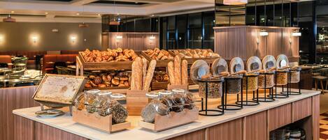A buffet counter with various food items, including bread and jars of condiments.