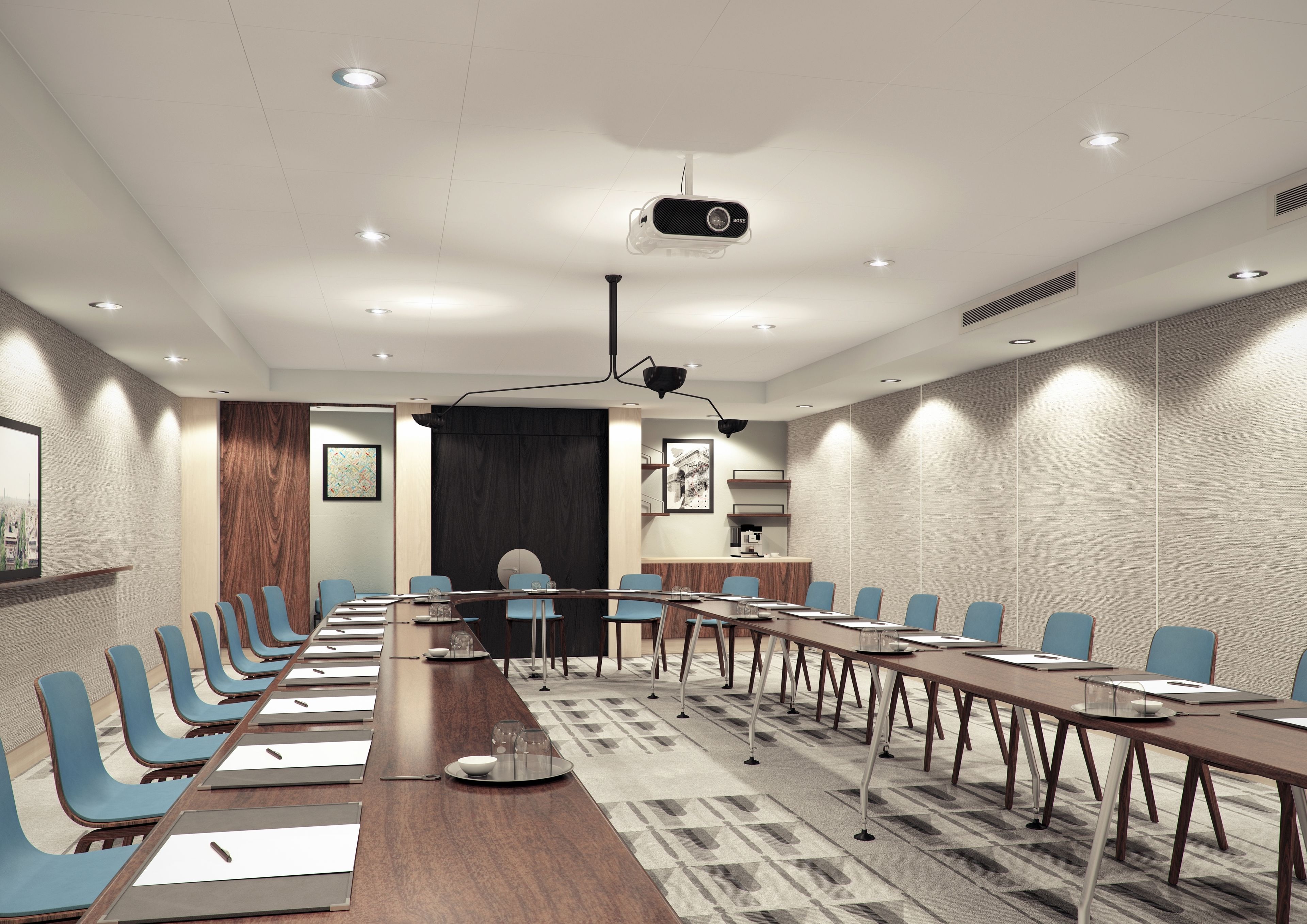 Un salón de conferencias con una larga mesa, sillas azules, un proyector y una máquina de café.