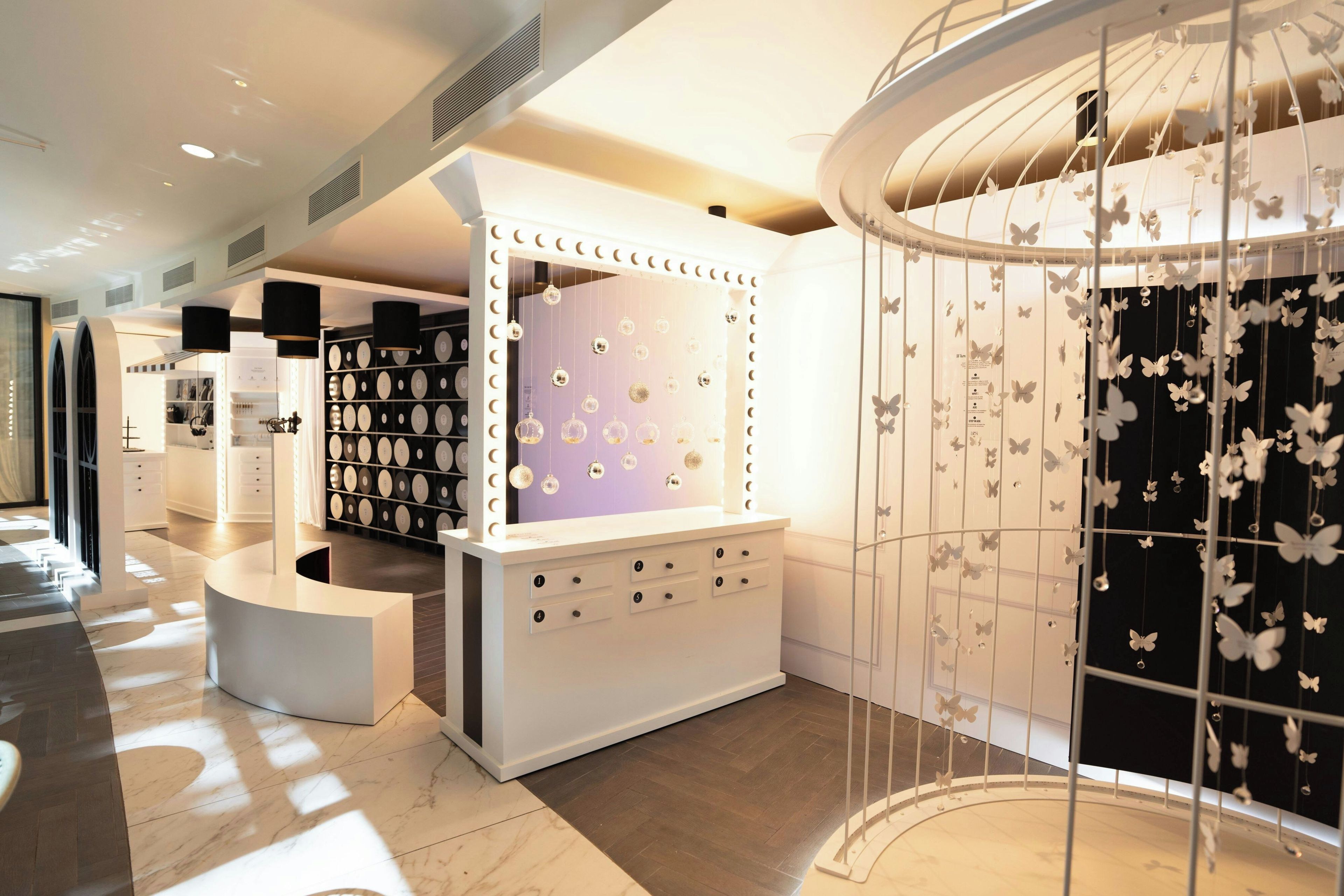 Un intérieur moderne avec un coin coiffeuse comprenant un miroir avec éclairage intégré, un présentoir à bijoux et une décoration murale sur le thème des papillons.
