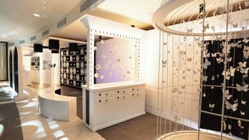 A modern interior with a vanity area featuring a mirror with lights, a jewelry display, and a butterfly-themed wall decoration.