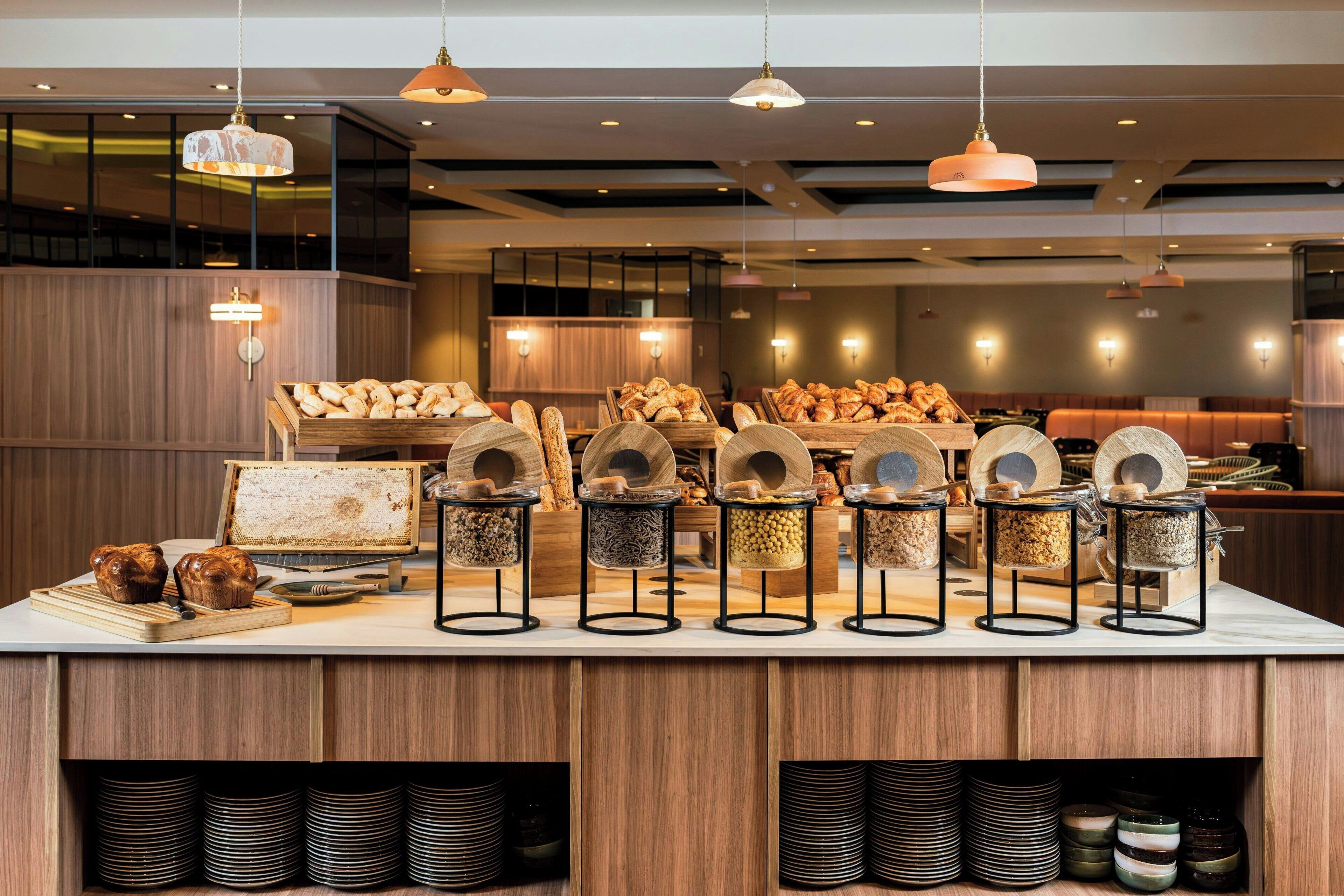 A buffet area with wooden counters, bread, and various food containers.