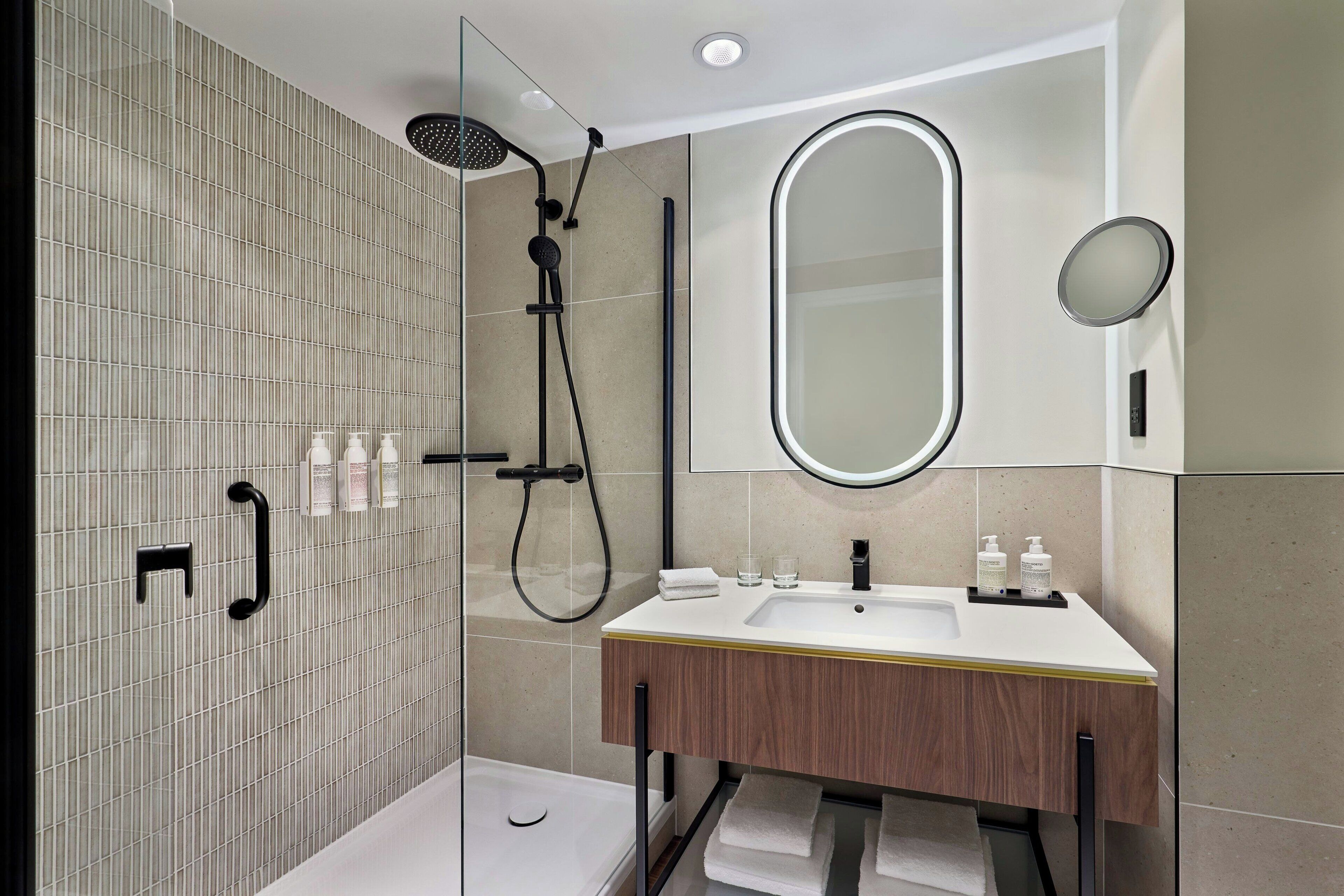 A modern bathroom with a shower, a sink, and a mirror.