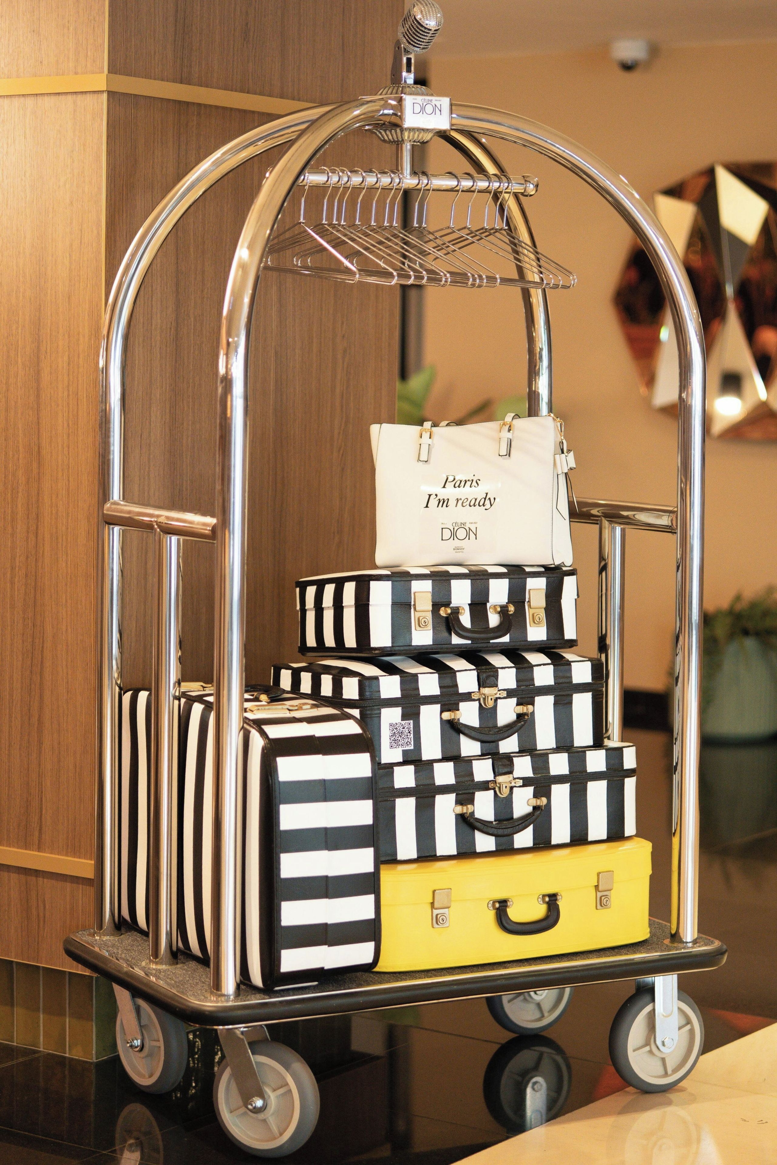 A luggage cart with multiple suitcases, including a white bag with text and a yellow suitcase.