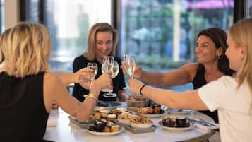 Un grupo de personas brindando con copas de vino alrededor de una mesa con diversos pasteles y postres.