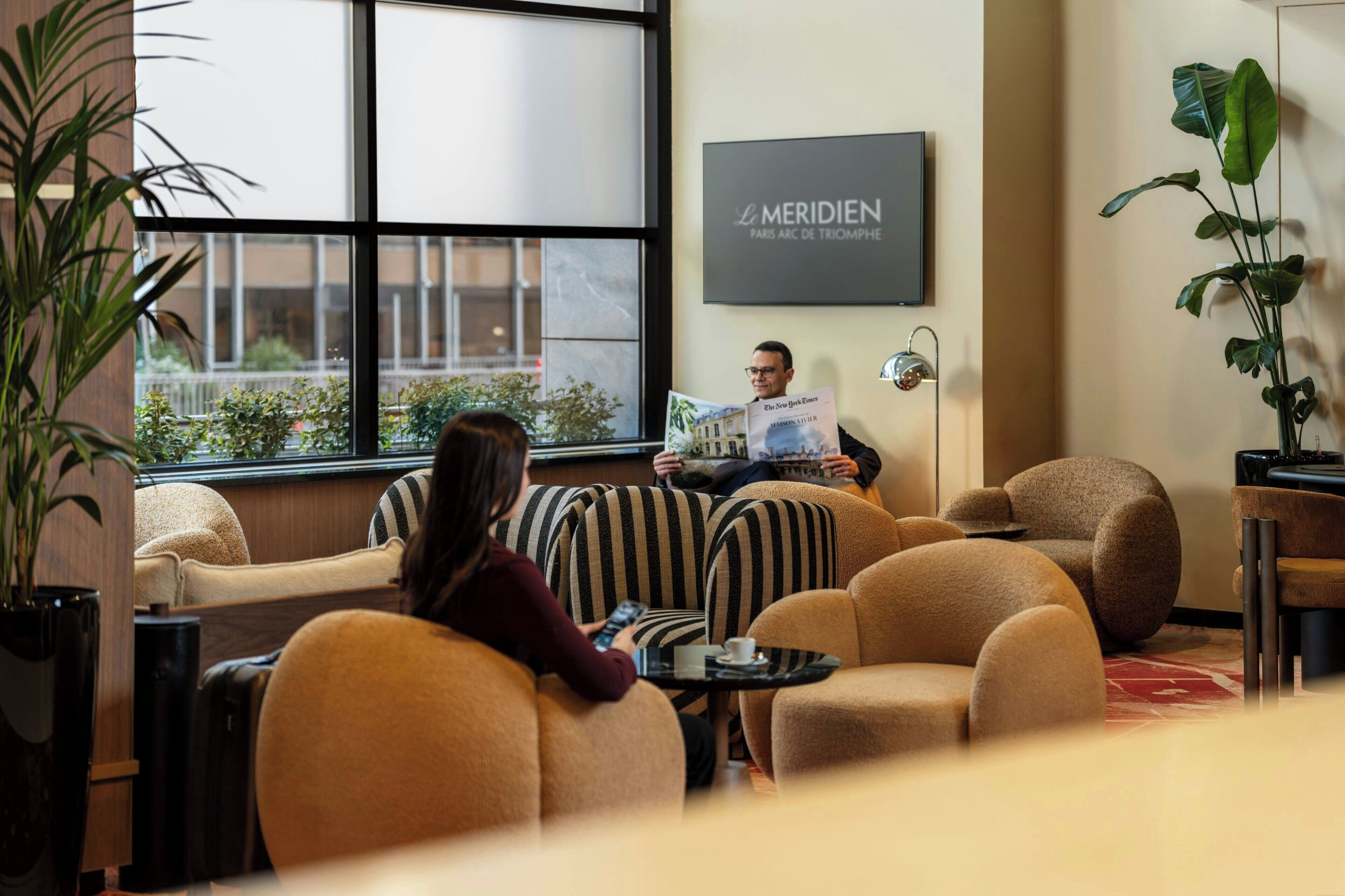 Un'area lounge moderna con posti a sedere comodi, un'ampia finestra e una targa appesa al muro.