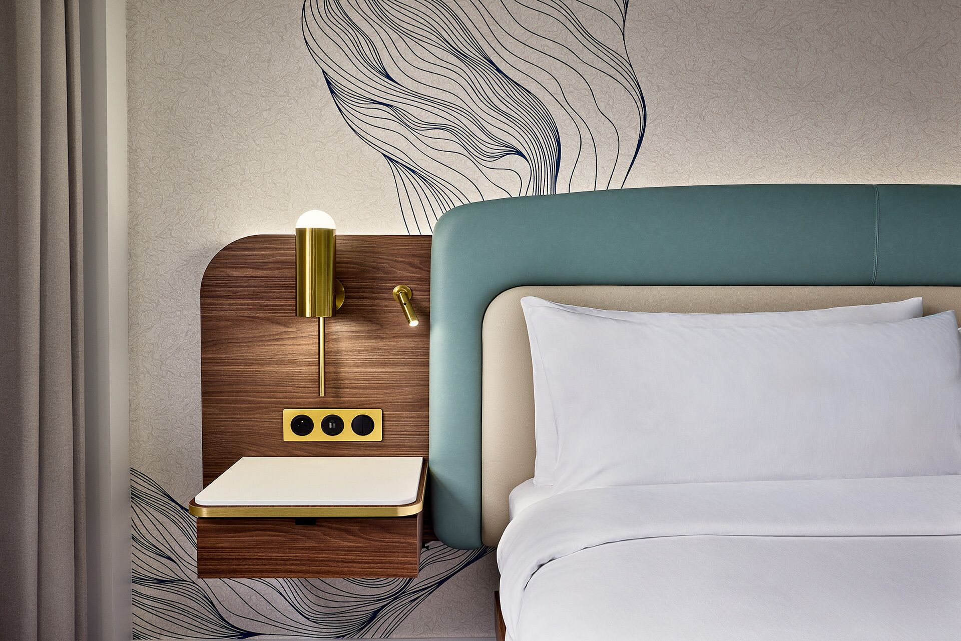 A neatly arranged hotel room with a bed, a bedside table with a lamp, and a wall art piece.