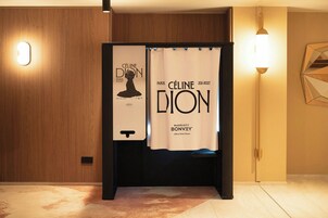 A hotel room with a wooden panel wall, a black partition, and a white curtain with text.