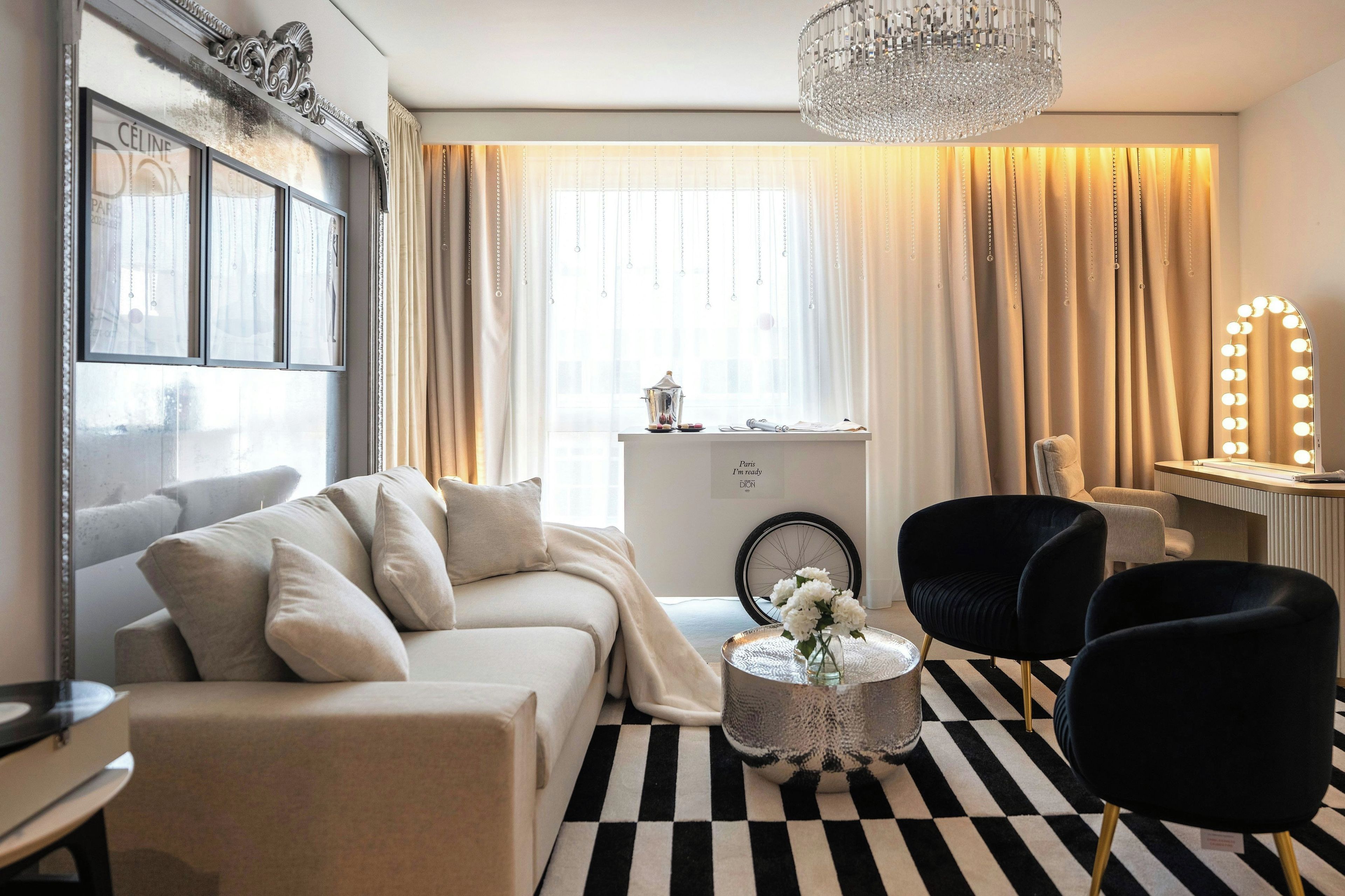 Un salon moderne comprenant un canapé, des fauteuils, une table basse, un miroir décoratif et un lustre.
