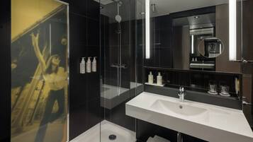 Un baño moderno con cabina de ducha de vidrio, un espejo grande y dos lavamanos.