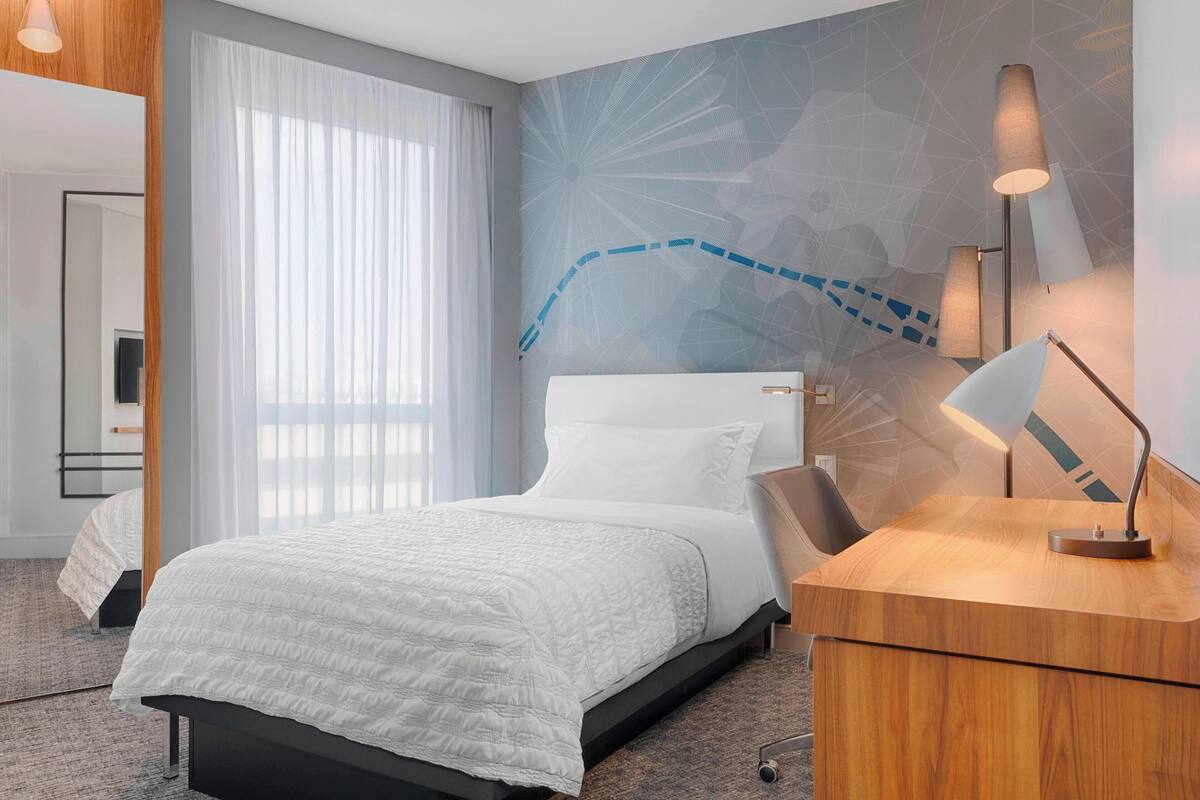 Una habitación de hotel con una cama, un escritorio y una pared con diseño geométrico.