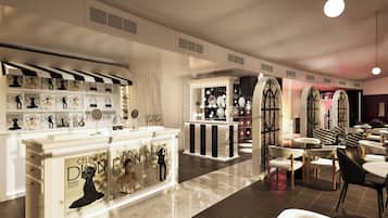 Un intérieur moderne avec un comptoir central où sont exposés des magazines de mode, un espace salon avec des tables et des chaises, et un coin beauté avec des miroirs et des éclairages.