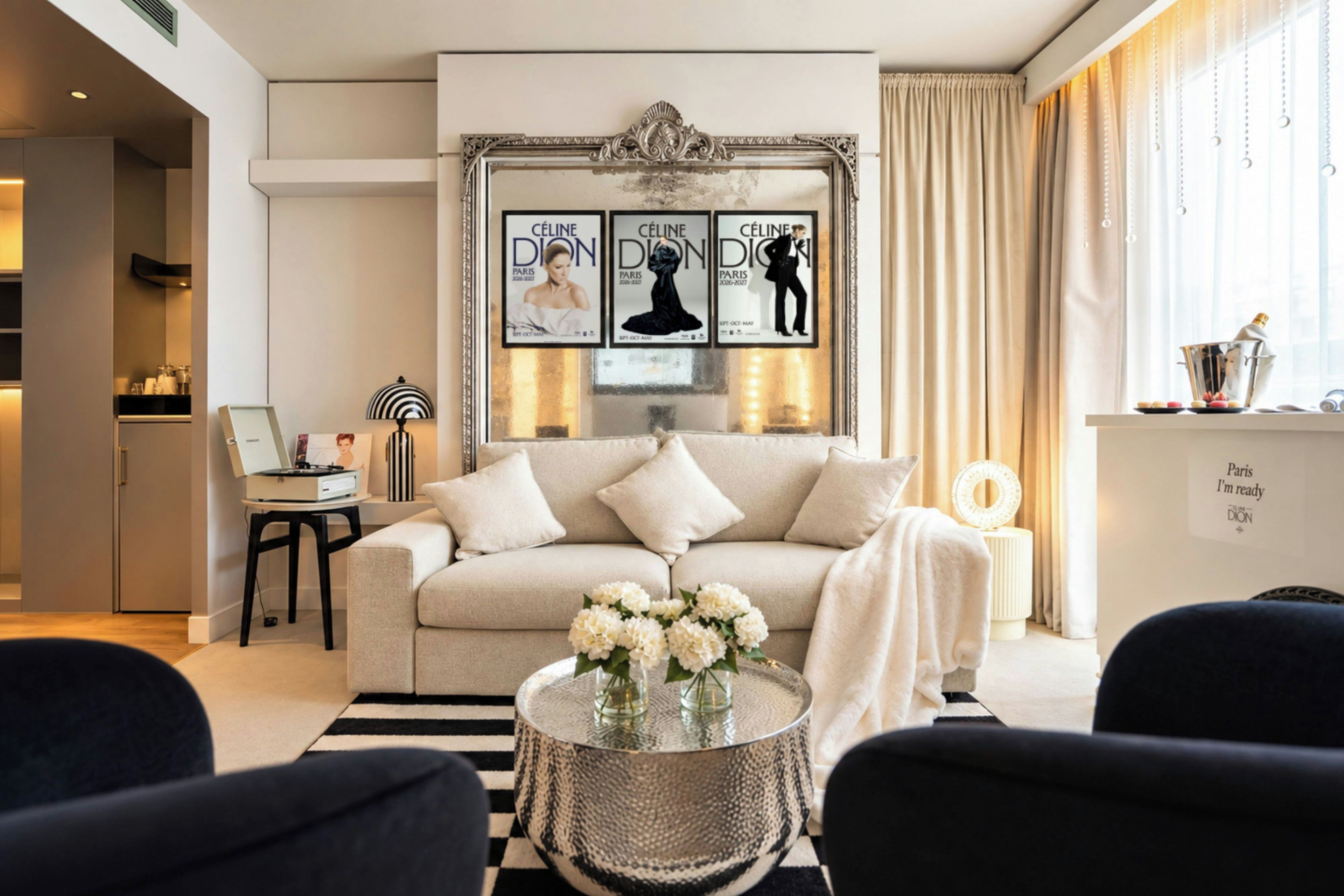A modern living room with a sofa, a coffee table with flowers, and a wall with framed posters.