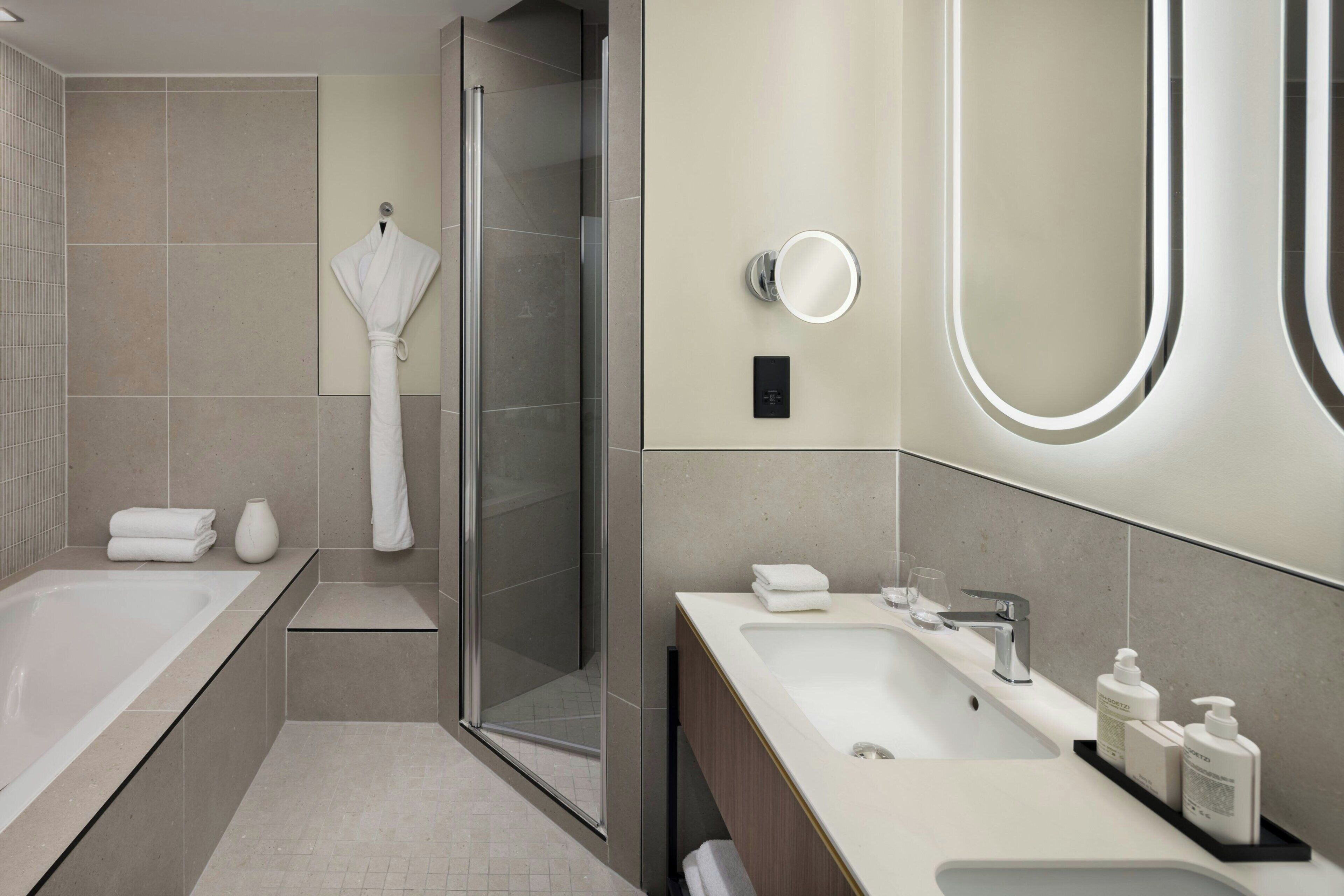 A modern bathroom with a bathtub, a shower, and a vanity with a mirror.