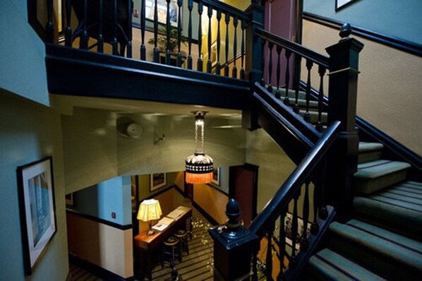 A multi-level interior with a staircase, a desk with a lamp, and a hanging light fixture.