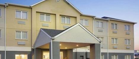A multi-story hotel with a covered entrance and a parking lot.