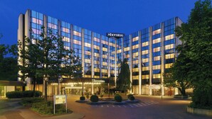 A Sheraton hotel with a modern glass facade, a well-lit entrance, and a landscaped courtyard. - Sheraton Essen Hotel (Essen)