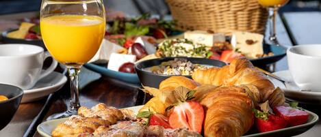 A breakfast setting with croissants, strawberries, and orange juice on a wooden table.
