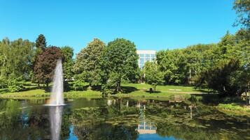 Een park met een fontein, bomen en een gebouw op de achtergrond.