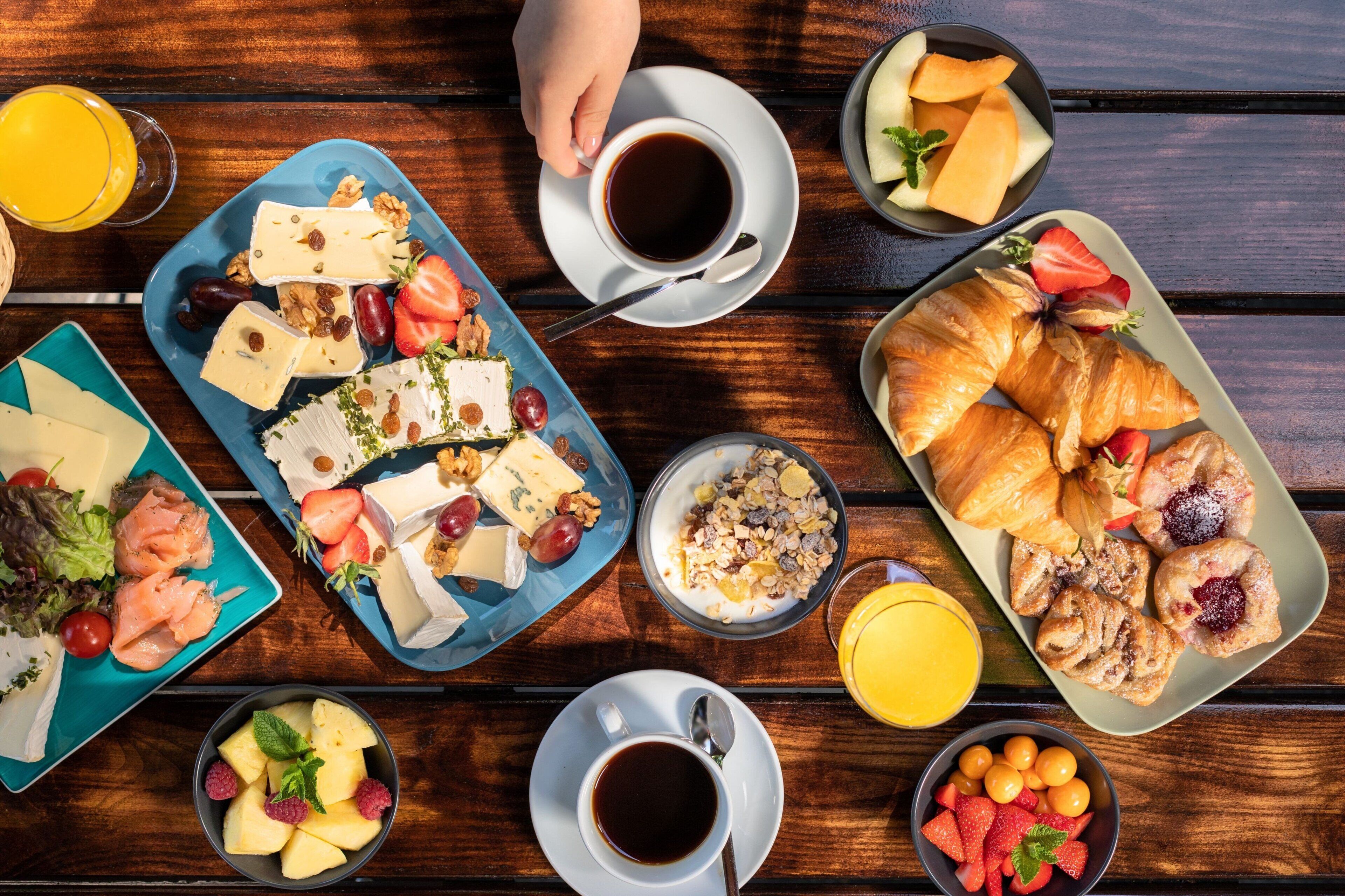 Una mesa de madera con una variedad de alimentos y bebidas para el desayuno.
