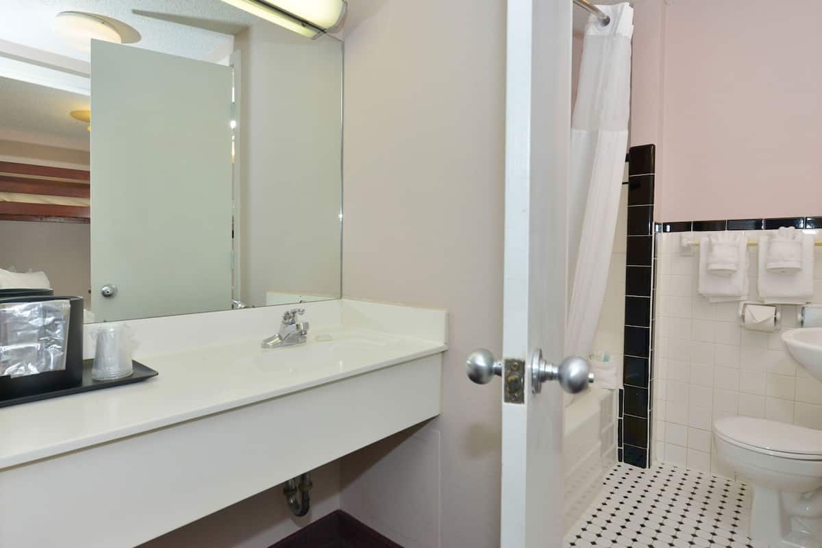 A bathroom with a white sink, a mirror, a shower curtain, a toilet, and a towel rack.