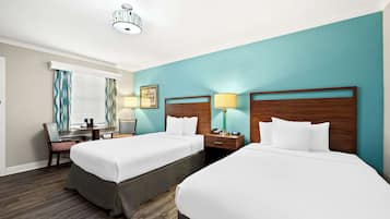 A hotel room with two beds, a desk, and a chair.