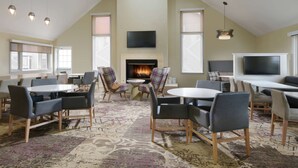 A spacious room with a fireplace, multiple seating areas, and a large flat-screen TV mounted on the wall.