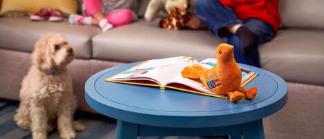 A living room with a round blue table, a sofa, and two children playing with toys.