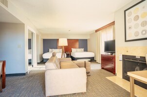 Una habitación de hotel con cama, sofá, televisión y chimenea.