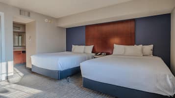 A hotel room with two beds, a wooden headboard, a telephone, and a small table.