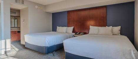 A hotel room with two beds, a wooden headboard, a telephone, and a small table.