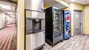 A hotel corridor with a vending machine, a refrigerator, and a door. - Quality Inn Poughkeepsie (Poughkeepsie)
