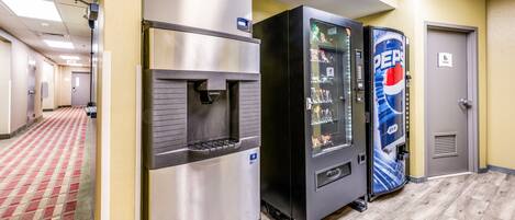A hotel corridor with a vending machine, a refrigerator, and a door.