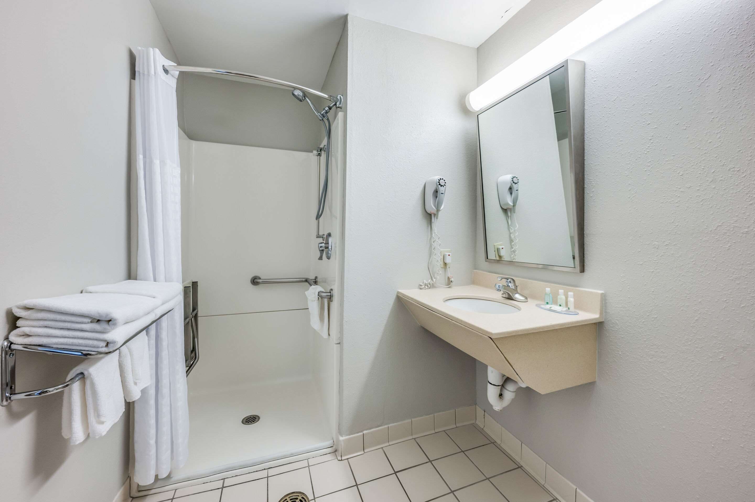 A modern bathroom with a walk-in shower, a vanity with a sink, and a large mirror.
