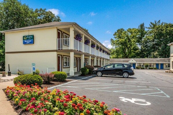 A motel with a parking lot, a black car parked, and colorful flowers in the foreground.