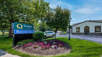A Quality Inn by Choice Hotels sign with a landscaped flower bed in front.