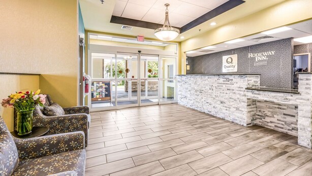 A hotel reception area with a reception desk, a waiting area with sofas, and a glass door entrance. - Quality Inn Poughkeepsie (Poughkeepsie)