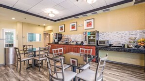 A modern kitchen with a central island, a dining area with chairs, and a refrigerator. - Quality Inn Poughkeepsie (Poughkeepsie)