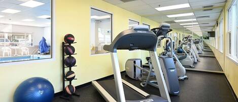 A gym with treadmills, exercise balls, and mirrors on the walls.