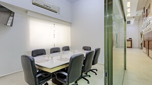A conference room with a long table, black chairs, and a whiteboard.