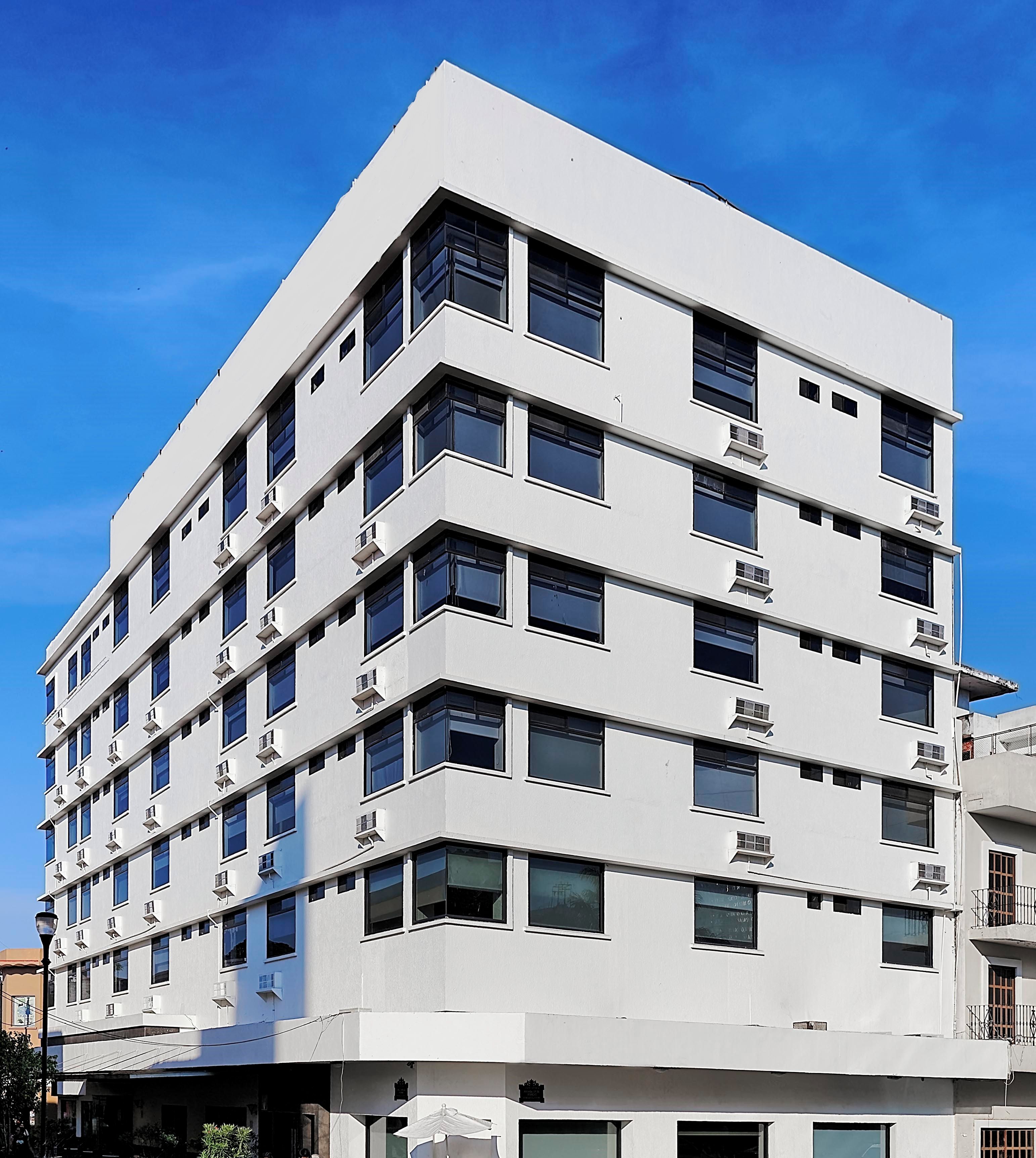 Ein mehrstöckiges Gebäude mit modernem architektonischen Design, das eine Reihe von rechteckigen Fenstern und Klimaanlagen aufweist.