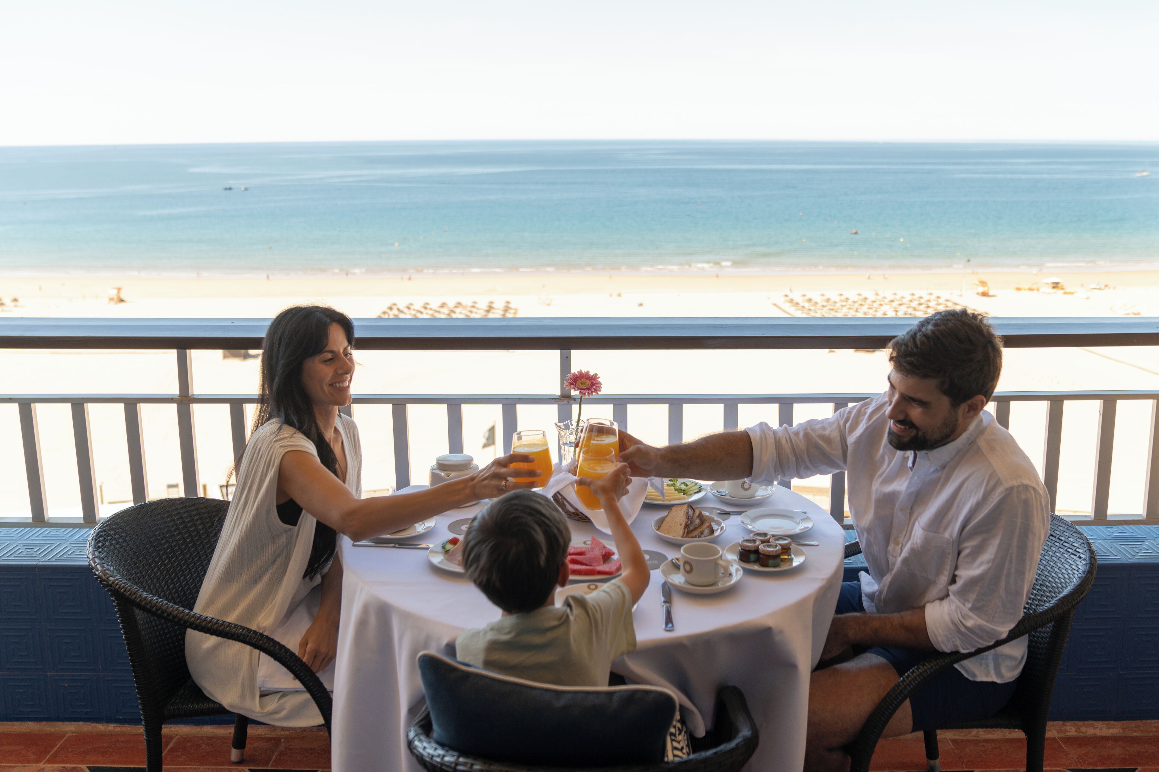 A family dining at a table with a view of the beach.